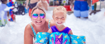 Mom and Daughter at water park playing in a pile of foam-like substance.